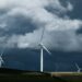 white wind turbines on green grass field under gray clouds